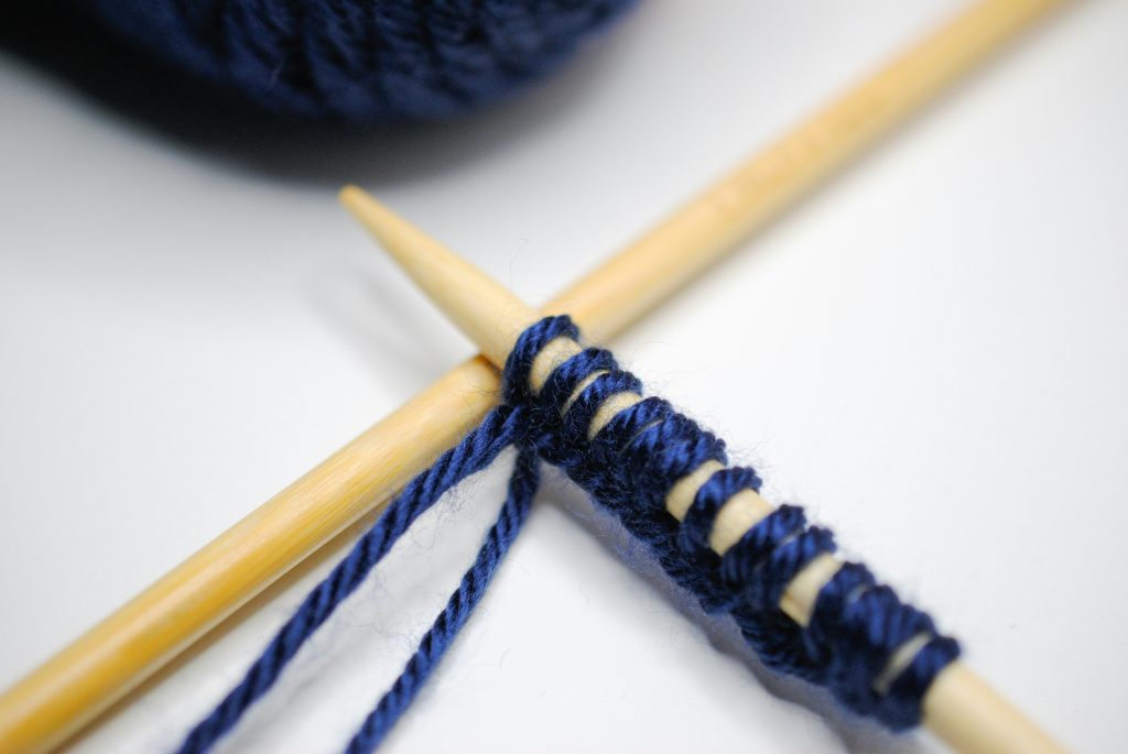 Bamboo knitting needles casting on with navy blue yarn